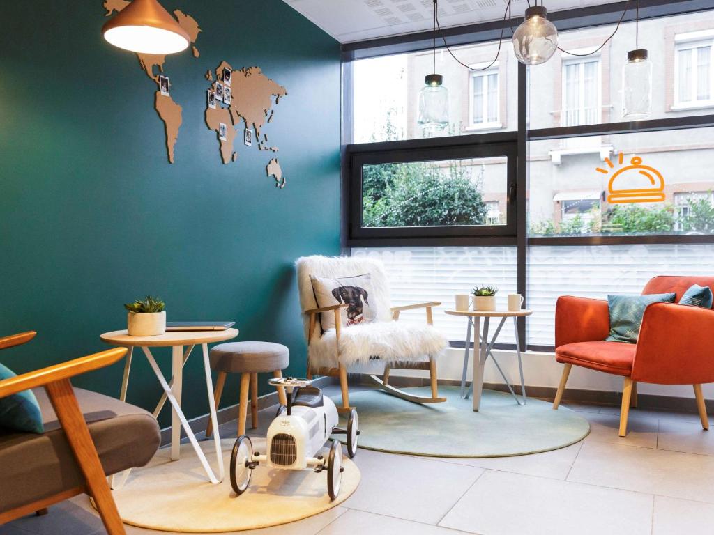 Cette chambre est dotée de chaises, de tables et d'un mur bleu. dans l'établissement Aparthotel Adagio Access Toulouse St Cyprien, à Toulouse