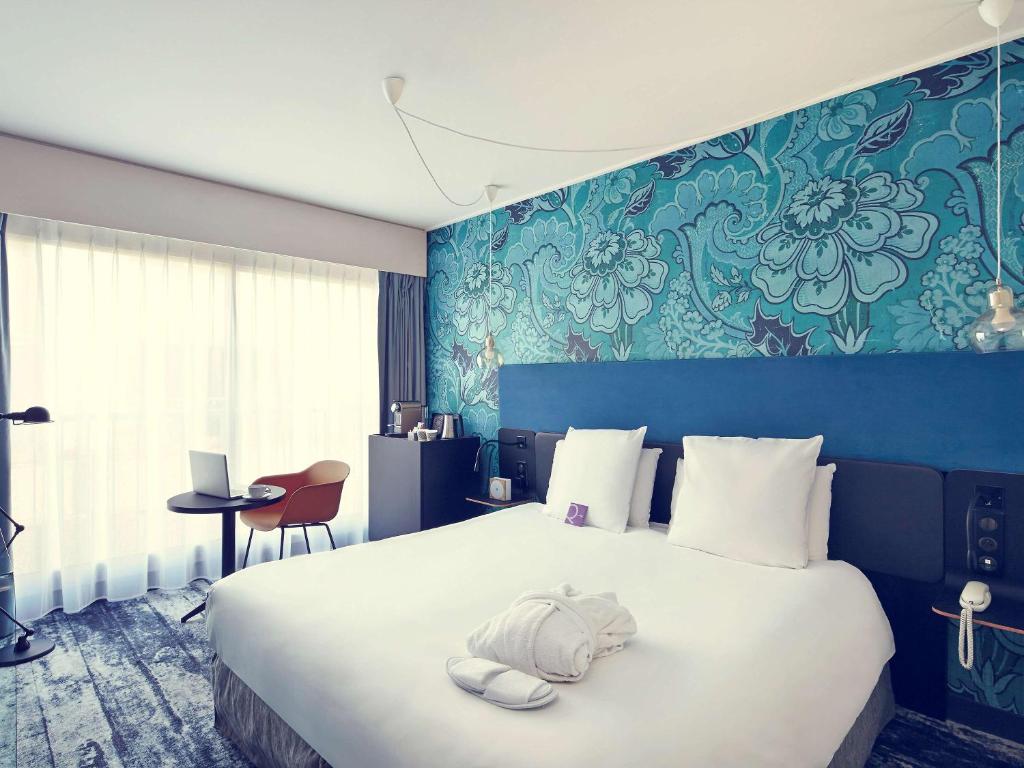 een slaapkamer met een groot bed met een blauwe muur bij Mercure Paris Bastille Saint Antoine in Parijs