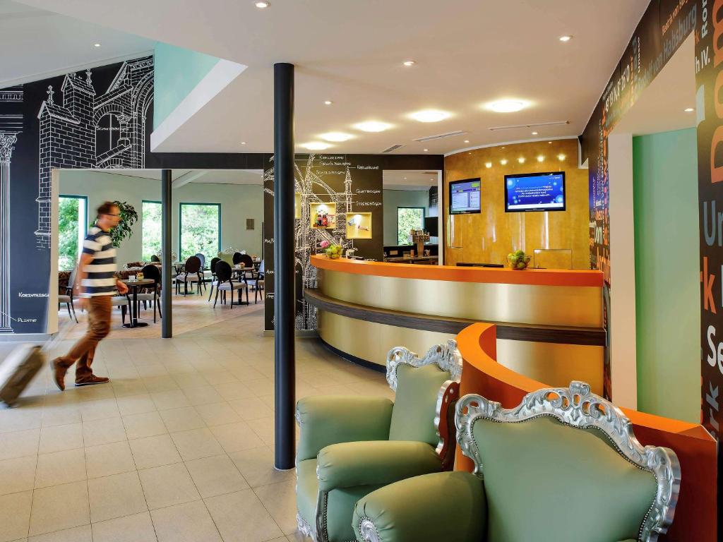 a man walking through a restaurant with chairs and a bar at ibis Styles Speyer in Speyer