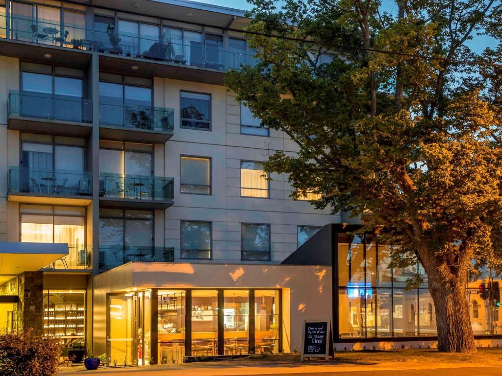 un edificio de oficinas con ventanas de cristal y un árbol en The Sebel Launceston, en Launceston