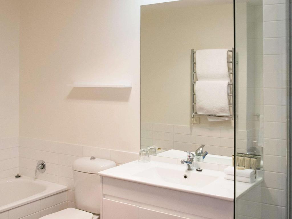 a white bathroom with a sink and a toilet at The Sebel Launceston in Launceston