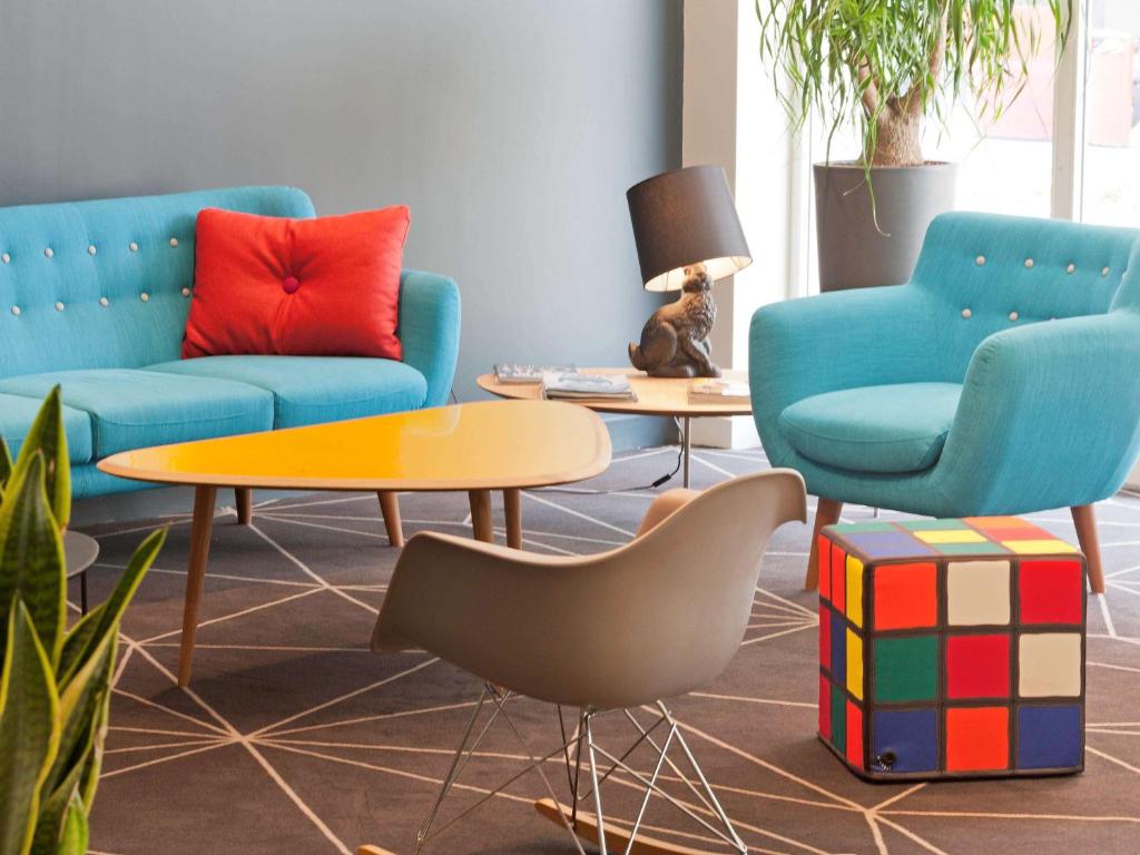 a living room with two blue chairs and a table at ibis Styles Roanne Centre Gare in Roanne