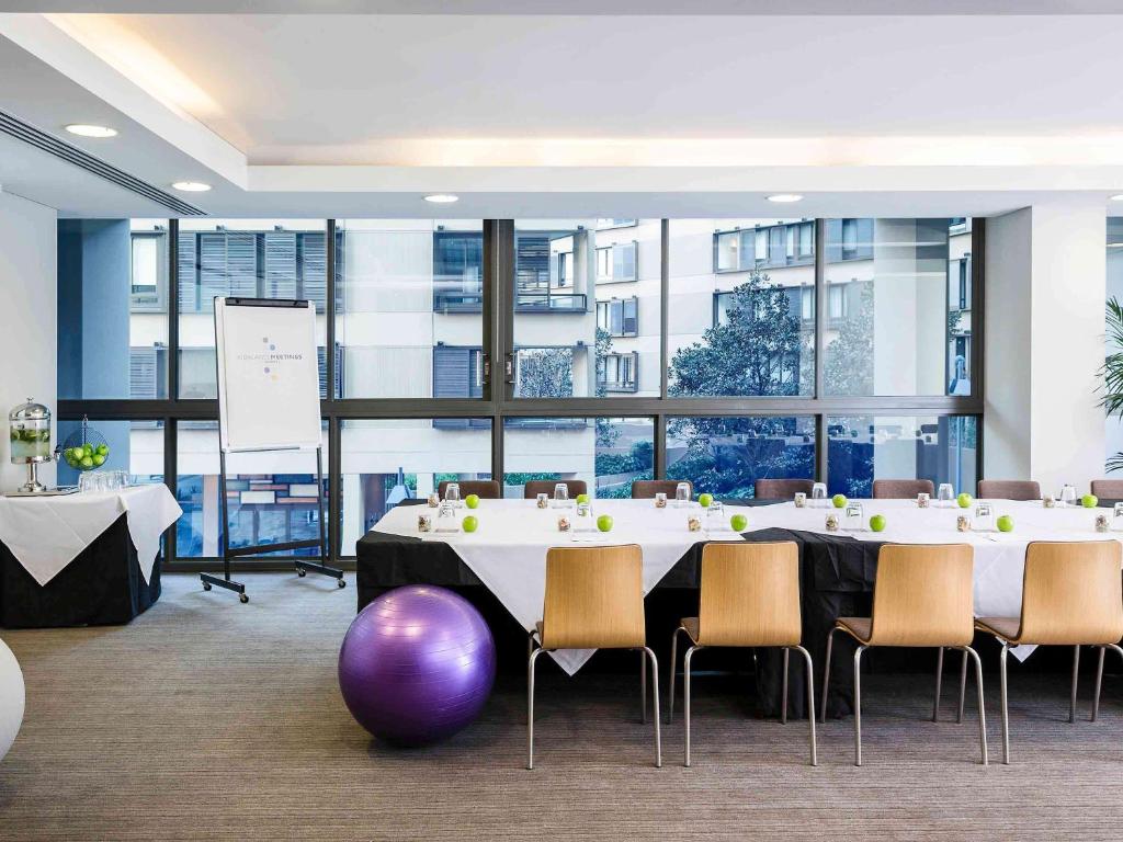 a meeting room with a large table and chairs at Novotel Newcastle Beach in Newcastle