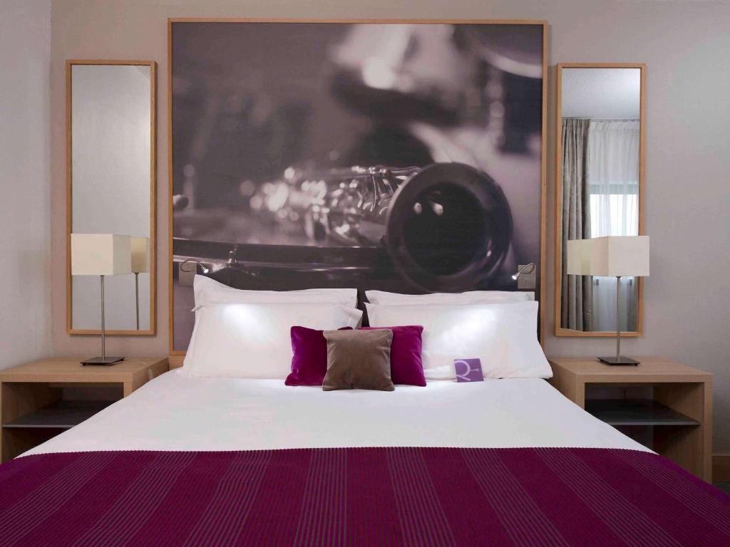 巴黎的住宿－巴黎愛樂廳拉維萊特19號美居酒店，一间卧室配有一张大床和两盏灯