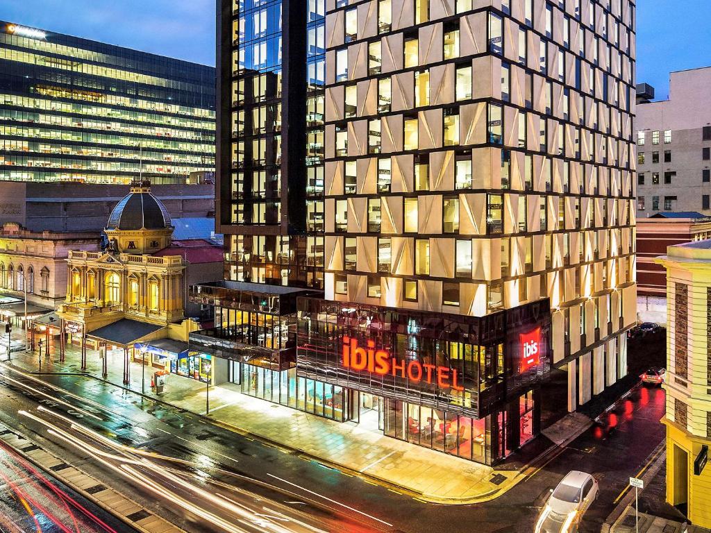 ibis Adelaide في أديلايد: مبنى طويل مع علامة فندق دبس بجوار شارع