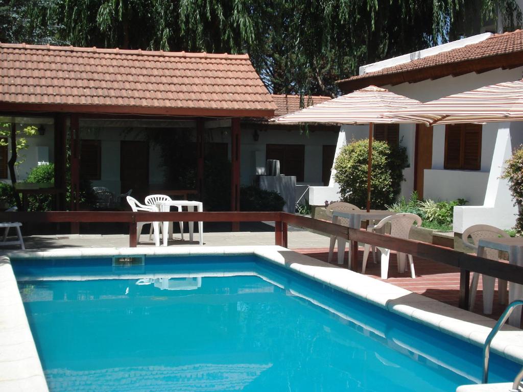 una piscina con sillas y sombrillas junto a una casa en El Agora en Villa General Belgrano