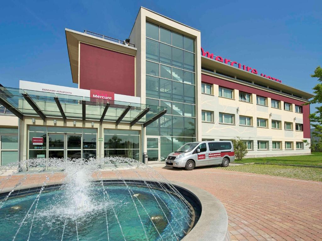 un edificio con una fontana di fronte a un edificio di Mercure Bergamo Aeroporto a Stezzano