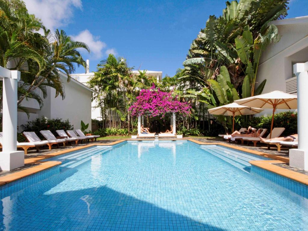 una piscina con sillas y sombrillas en un complejo en The Reef House Adults Retreat - Enjoy 28 Complimentary Inclusions en Palm Cove