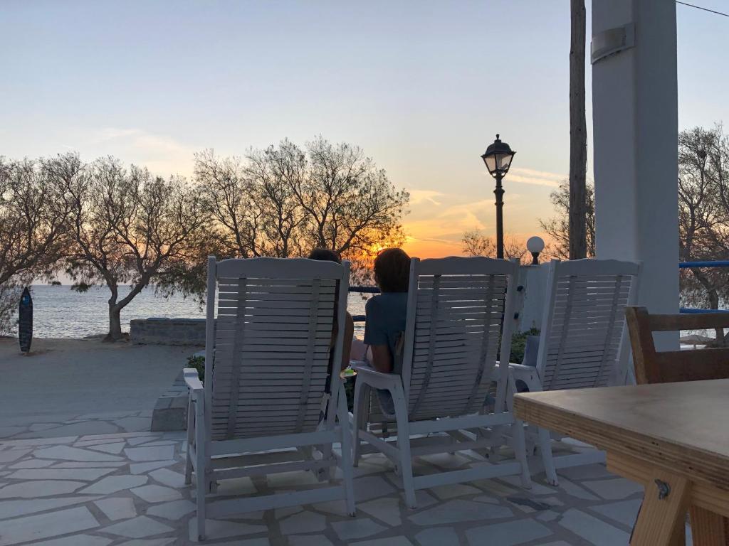 Zwei Leute sitzen auf Stühlen und beobachten den Sonnenuntergang. in der Unterkunft Akti Kastraki Beach in Kastraki Naxos