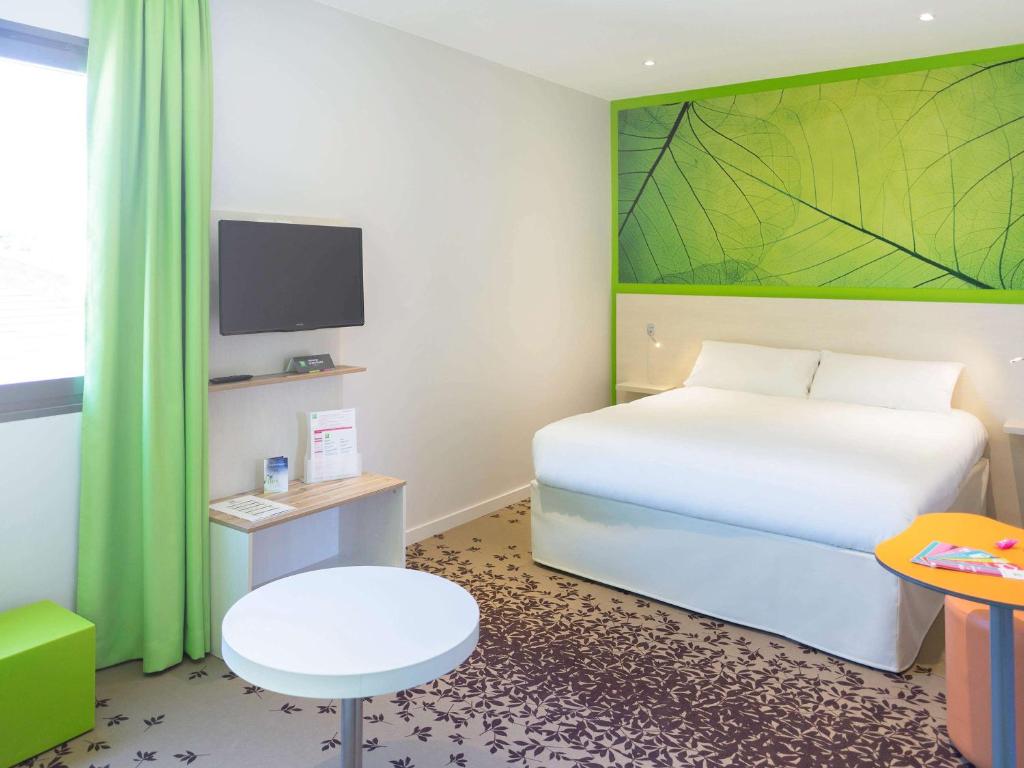 a bedroom with a white bed and a green wall at ibis styles Villeneuve Sur Lot in Villeneuve-sur-Lot