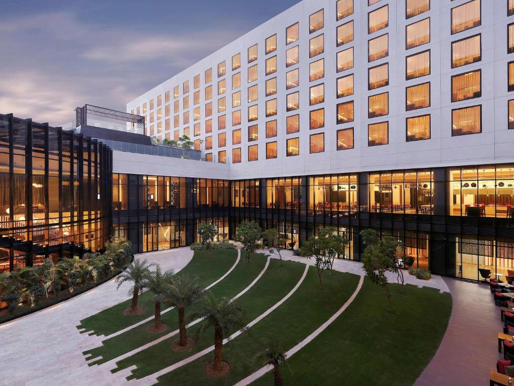 a rendering of a building with palm trees in front at Novotel New Delhi Aerocity- International Airport in New Delhi