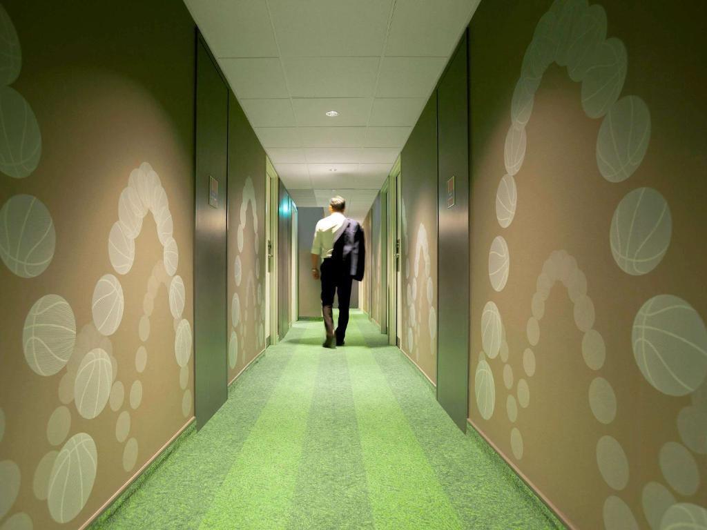 Un homme marchant dans un couloir dans l'établissement Ibis Styles Paris Massena Olympiades, à Paris