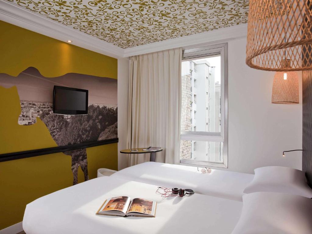 um quarto com uma cama branca e uma janela em ibis Styles Paris Buttes Chaumont em Paris
