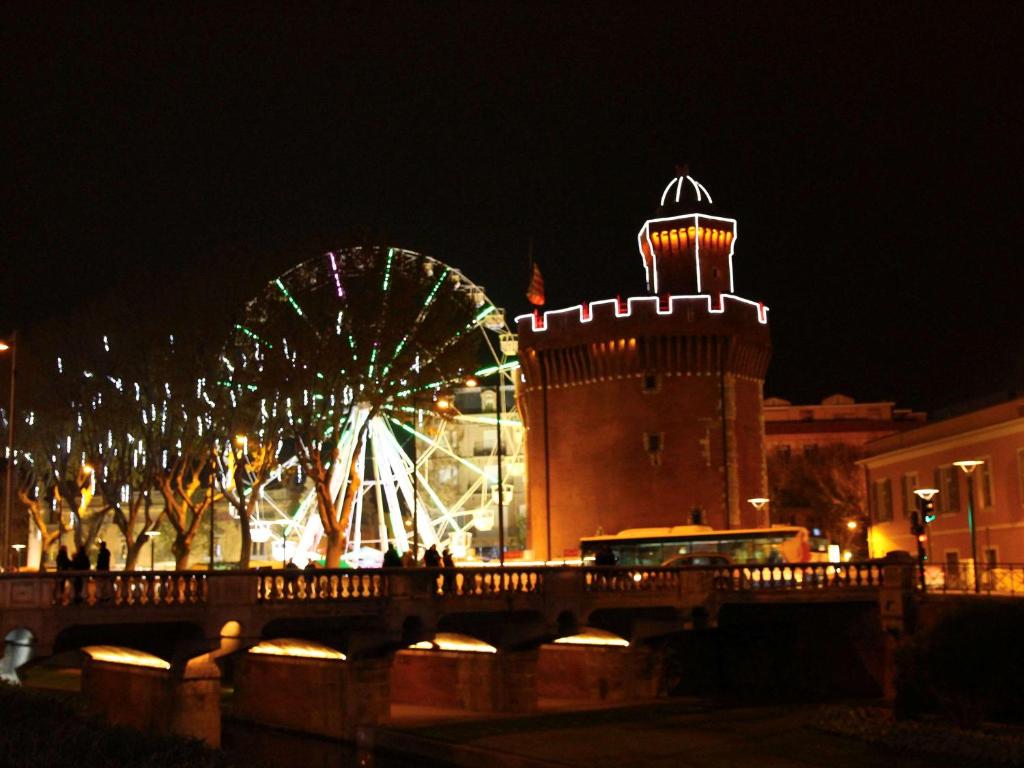 a ferris wheel in front of a city at night at HotelF1 Perpignan Sud in Perpignan