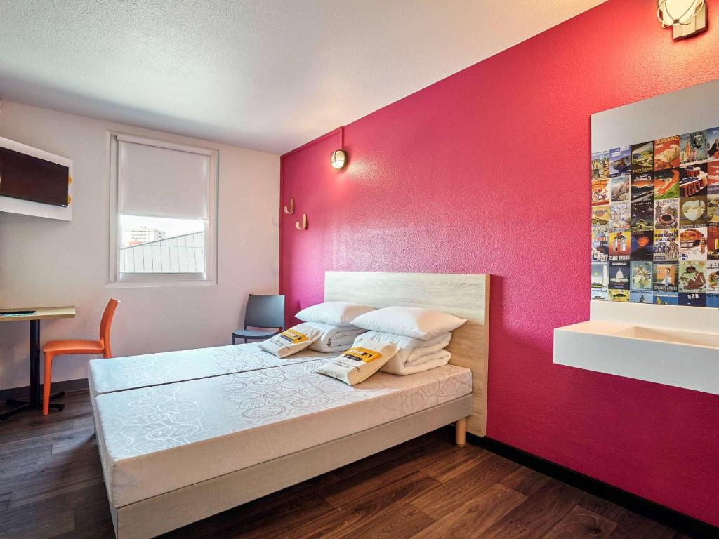 um quarto com uma cama com uma parede rosa em HotelF1 Perpignan Sud em Perpignan