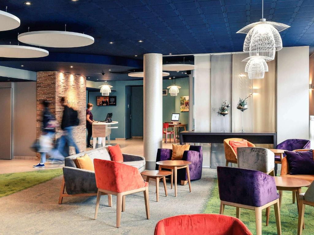 a lobby with colorful chairs and tables and people at Mercure Trouville Sur Mer in Trouville-sur-Mer
