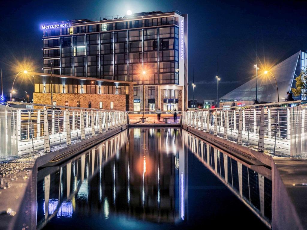 a building at night with a body of water at Mercure Cherbourg Centre Port in Cherbourg en Cotentin