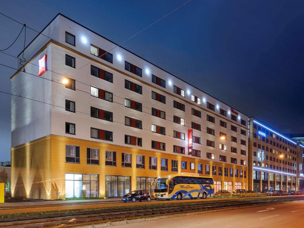 a large building with a bus parked in front of it at Ibis München City Arnulfpark in Munich