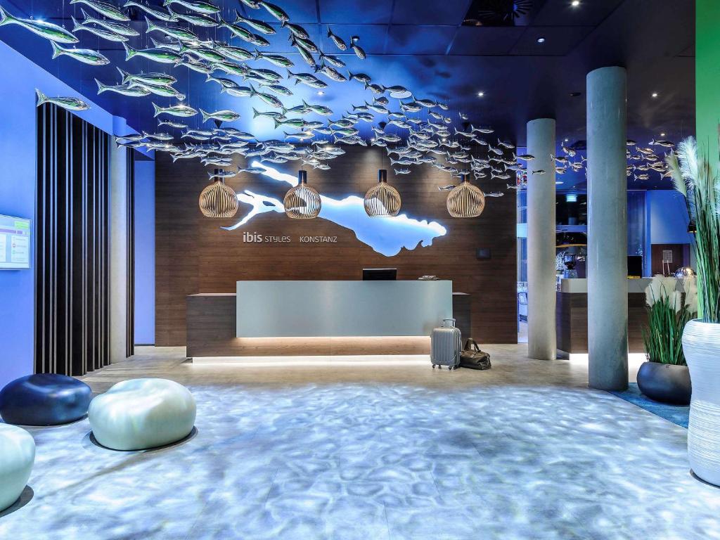 a lobby with a reception desk and a cloud ceiling at Ibis Styles Konstanz in Konstanz