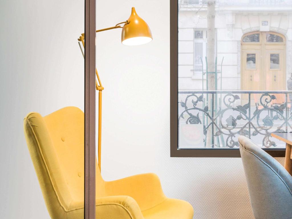 żółte krzesło i lampa obok okna w obiekcie Ibis Styles Paris Crimée La Villette w Paryżu