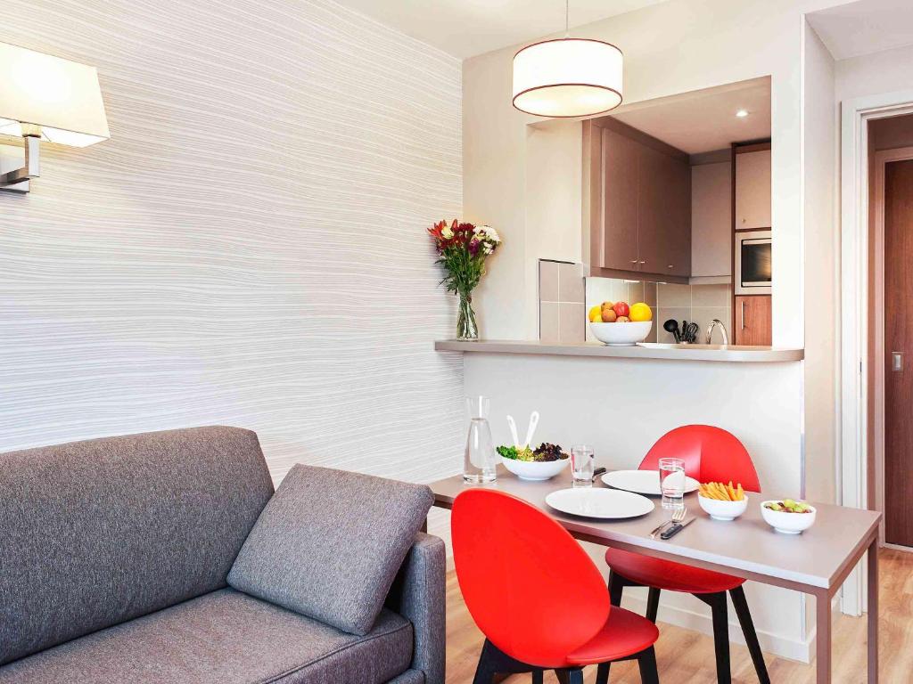 a living room with a couch and a table with red chairs at Aparthotel Adagio Birmingham City Centre in Birmingham