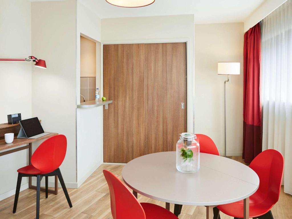 a room with a white table and red chairs at Aparthotel Adagio Birmingham City Centre in Birmingham