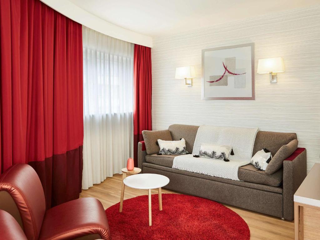 a living room with a couch and red curtains at Aparthotel Adagio Birmingham City Centre in Birmingham