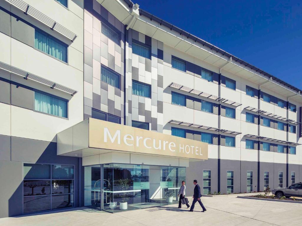 dwoje ludzi idzie przed Mercure hotel w obiekcie Mercure Newcastle Airport w mieście Newcastle