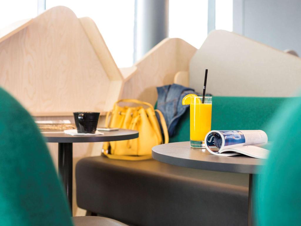 two tables in a room with a laptop and a drink at ibis Styles Paris Charles de Gaulle Airport in Roissy-en-France