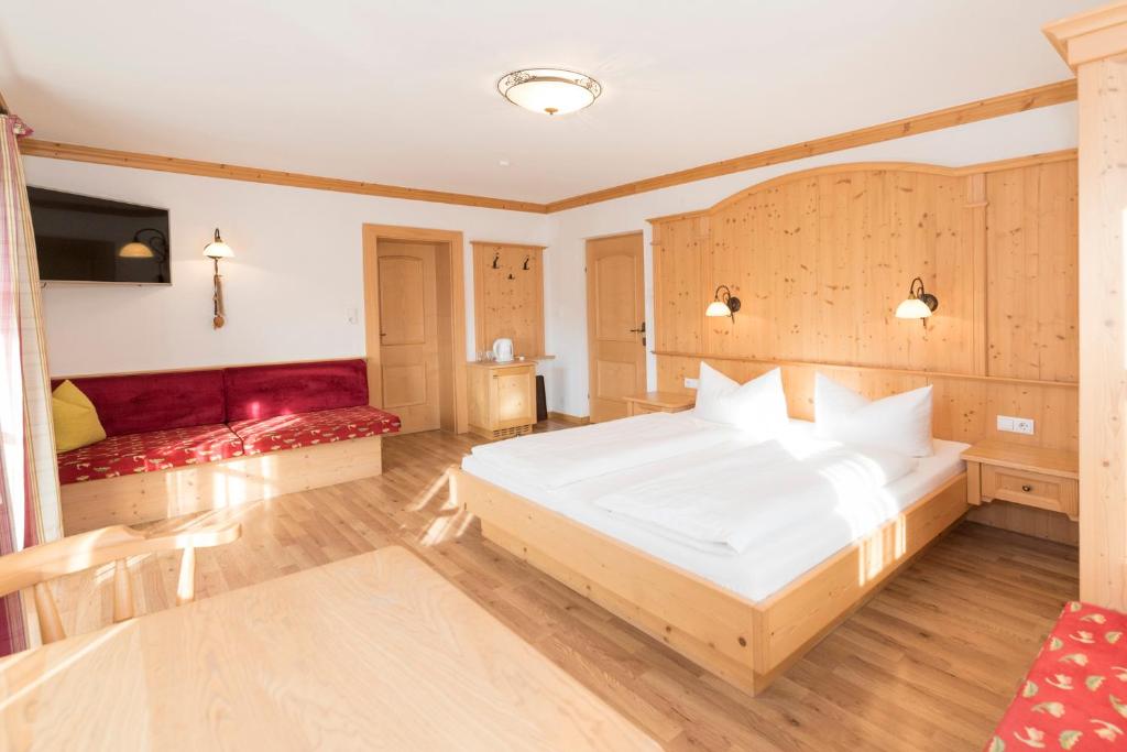 a bedroom with a large white bed and red seats at Das kleine, feine SONNWEND in Alpbach