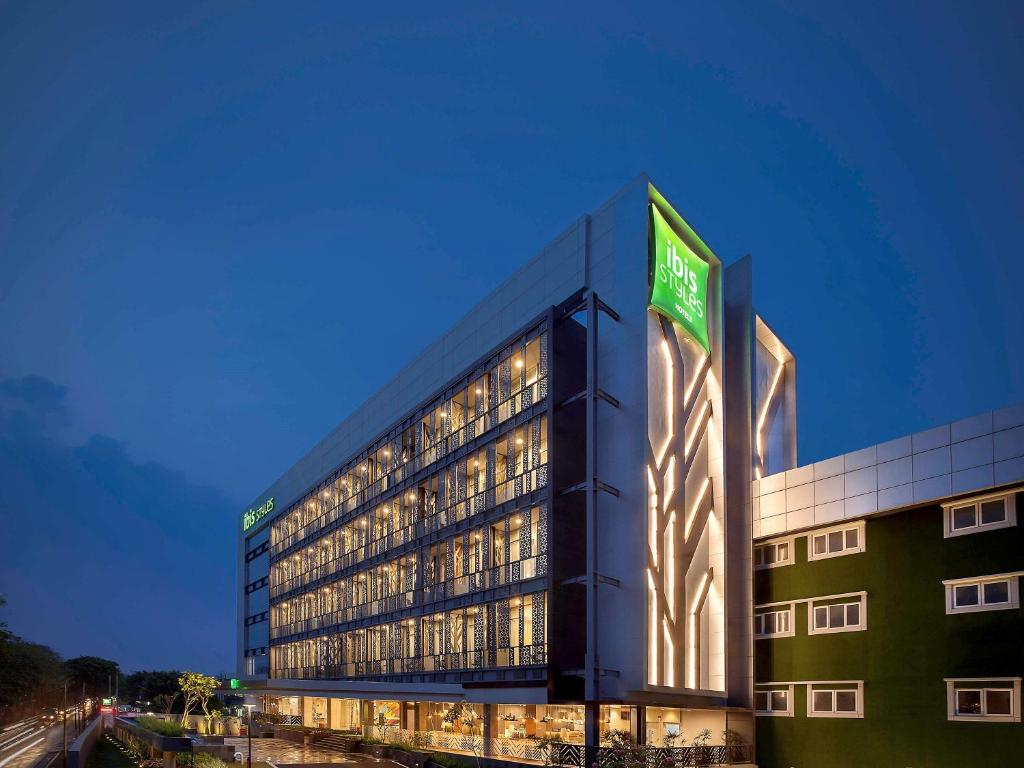 un gran edificio con un letrero verde. en Ibis Styles Jakarta Sunter, en Yakarta