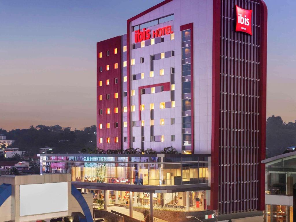 a tall red building with aidas motel sign on it at Ibis Manado City Center Boulevard in Manado