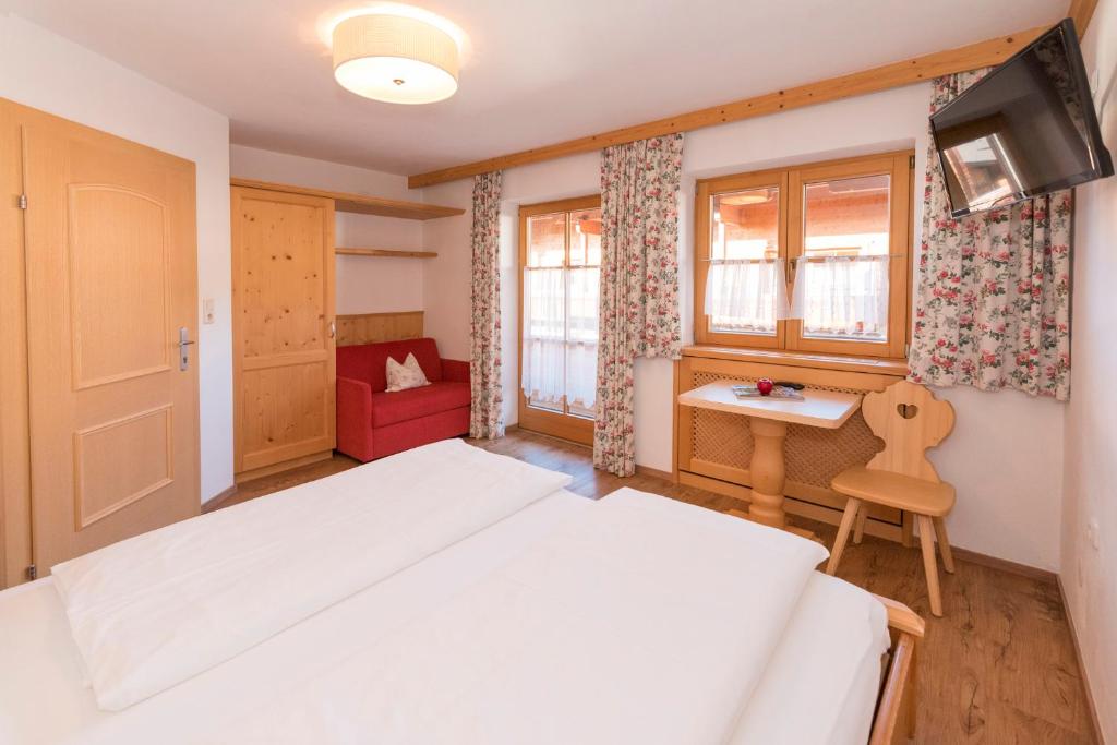 a bedroom with a white bed and a red chair at Das kleine, feine SONNWEND in Alpbach