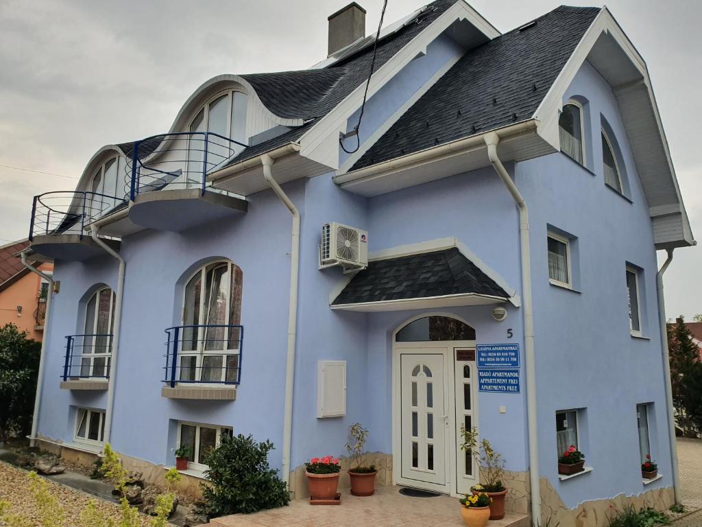 ein blaues Haus mit einer weißen Tür und einem Balkon in der Unterkunft Laguna Apartmanház in Hévíz