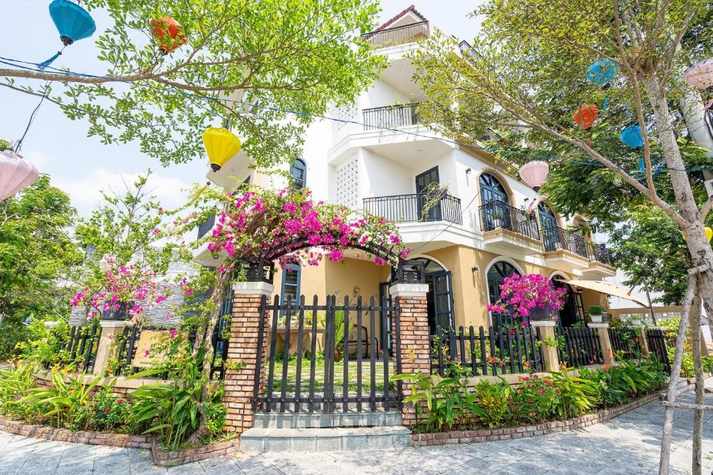 a house with flowers in front of a fence at Lami Villa Hoian 1 in Hoi An