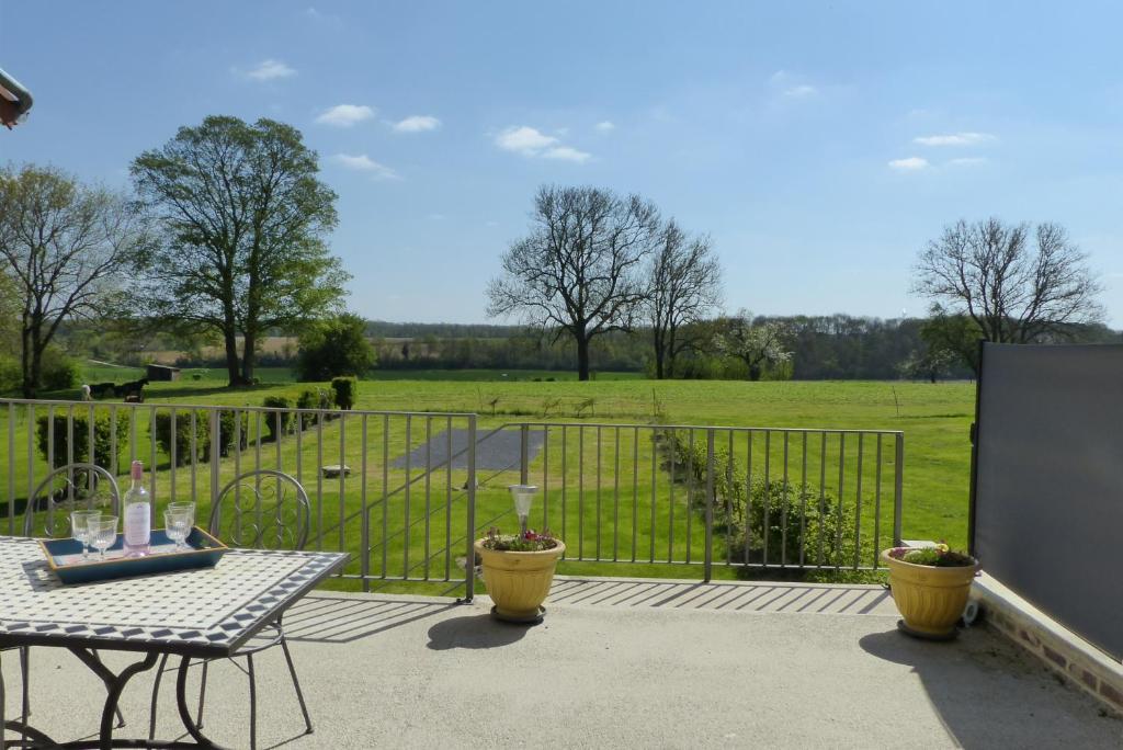 eine Terrasse mit einem Tisch, einem Zaun und einem Feld in der Unterkunft Gîte La Maison d'Edouard in Villers-Carbonnel