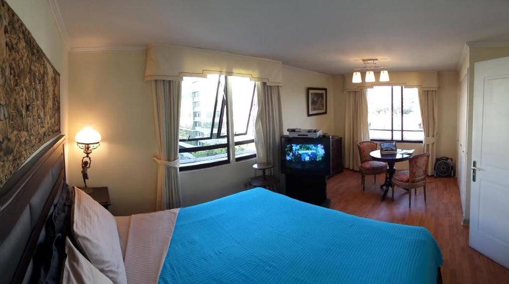 a bedroom with a blue bed and a table and windows at Costanera Center Apartment in Santiago