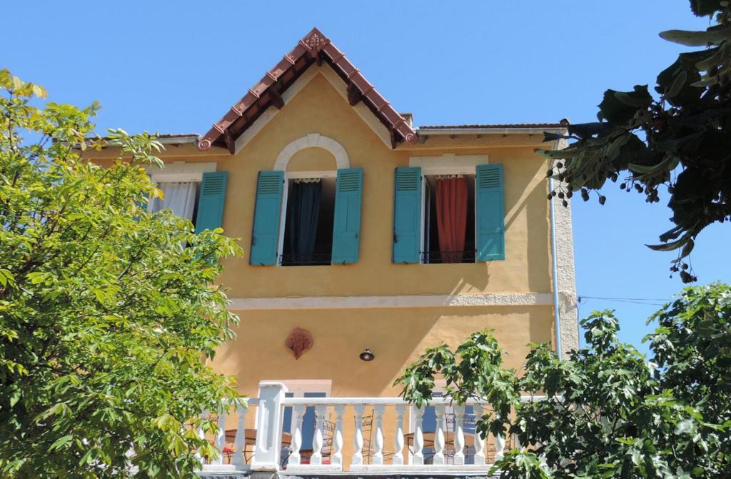 Maison jaune avec volets verts et terrasse couverte dans l'établissement 1001 Ocres, à Apt