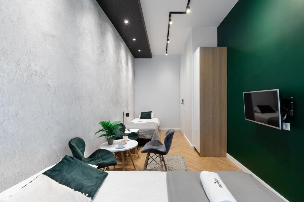 1 dormitorio con pared de acento verde y 2 camas y sillas en Rainbow Apartments 3, en Cracovia