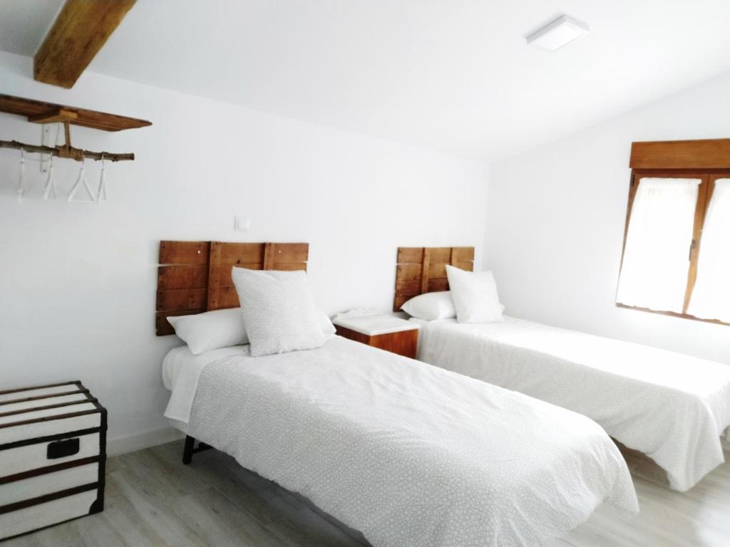 Dos camas en una habitación con paredes blancas. en Casa Rural Teresa, en El Molar