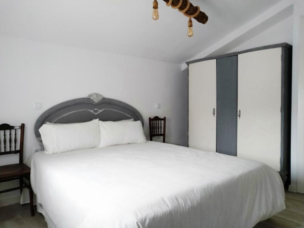 1 dormitorio con 1 cama blanca grande y 2 sillas en Casa Rural Teresa, en El Molar
