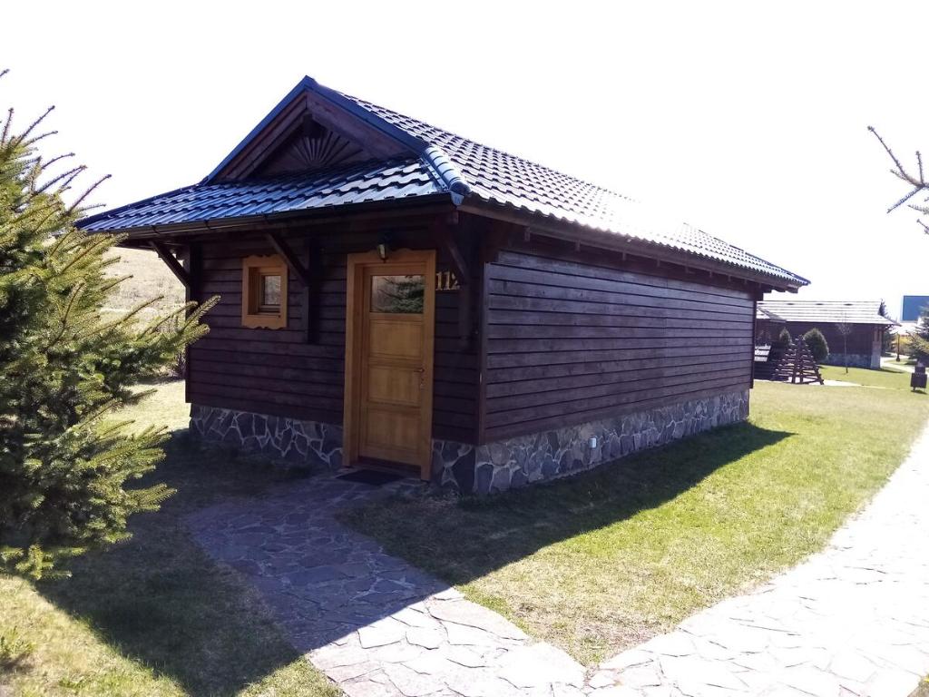 a small wooden cabin with a door in the grass at Chata Lucia 112 in Liptovský Mikuláš