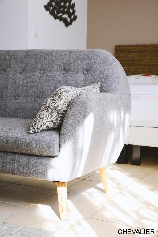a gray couch with a pillow on it next to a bed at Aux Premières Loges in Fécamp