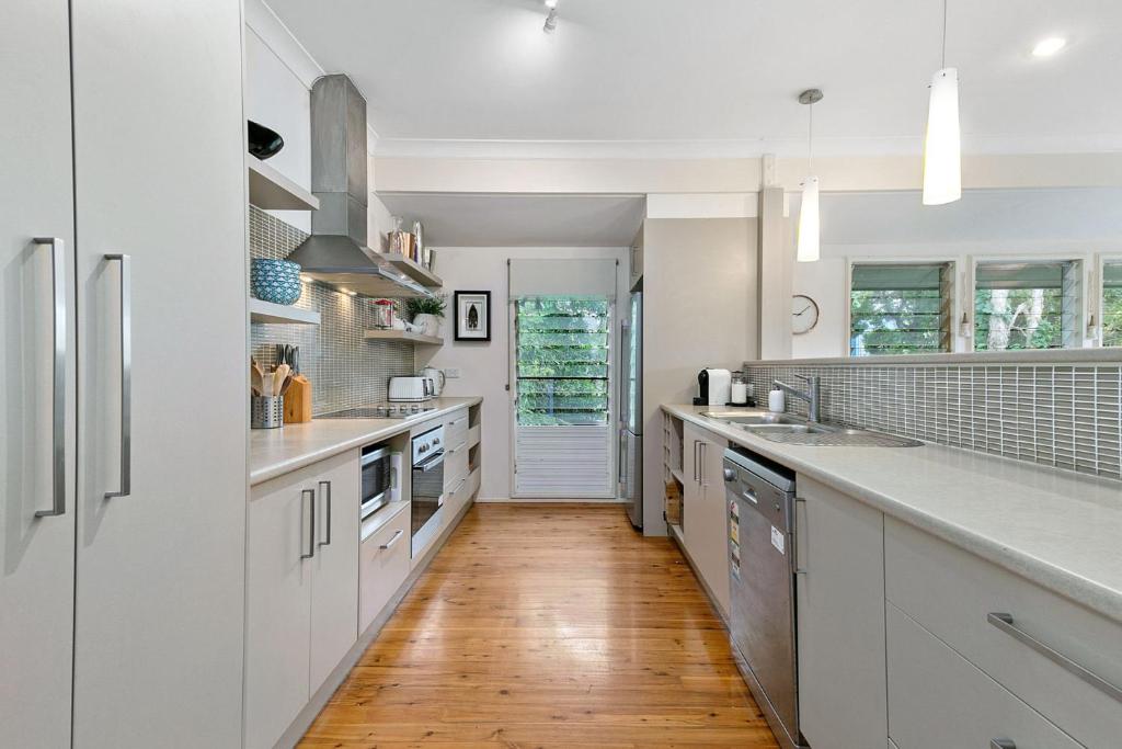 a kitchen with white cabinets and a hard wood floor at Grevillea in Point Lookout