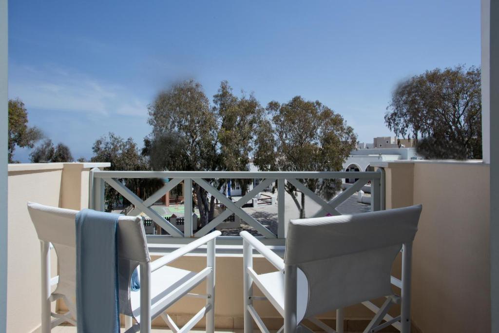 a balcony with chairs and a view of trees at Santorini Med Homes - Sunday Apartment in Mesaria