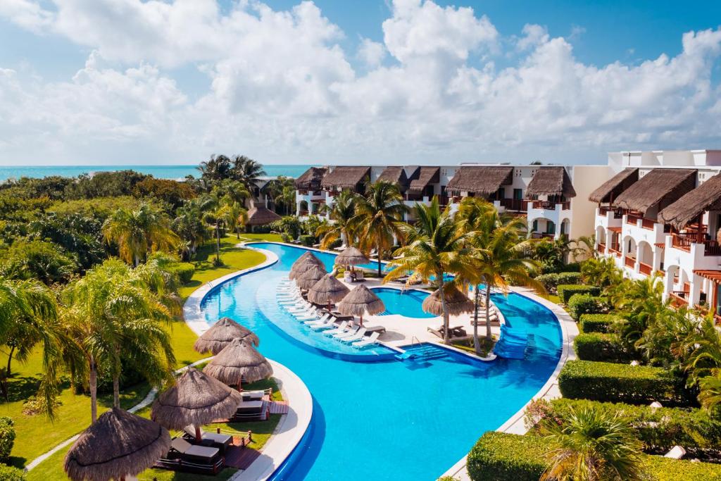 a beach with a pool, chairs, and tables at Valentin Imperial Riviera Maya All Inclusive - Adults Only in Puerto Morelos