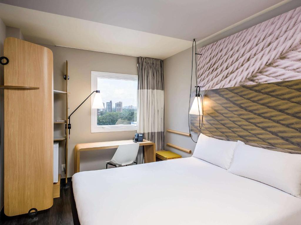 um quarto com uma grande cama branca e uma janela em ibis Fortaleza Centro de Eventos em Fortaleza