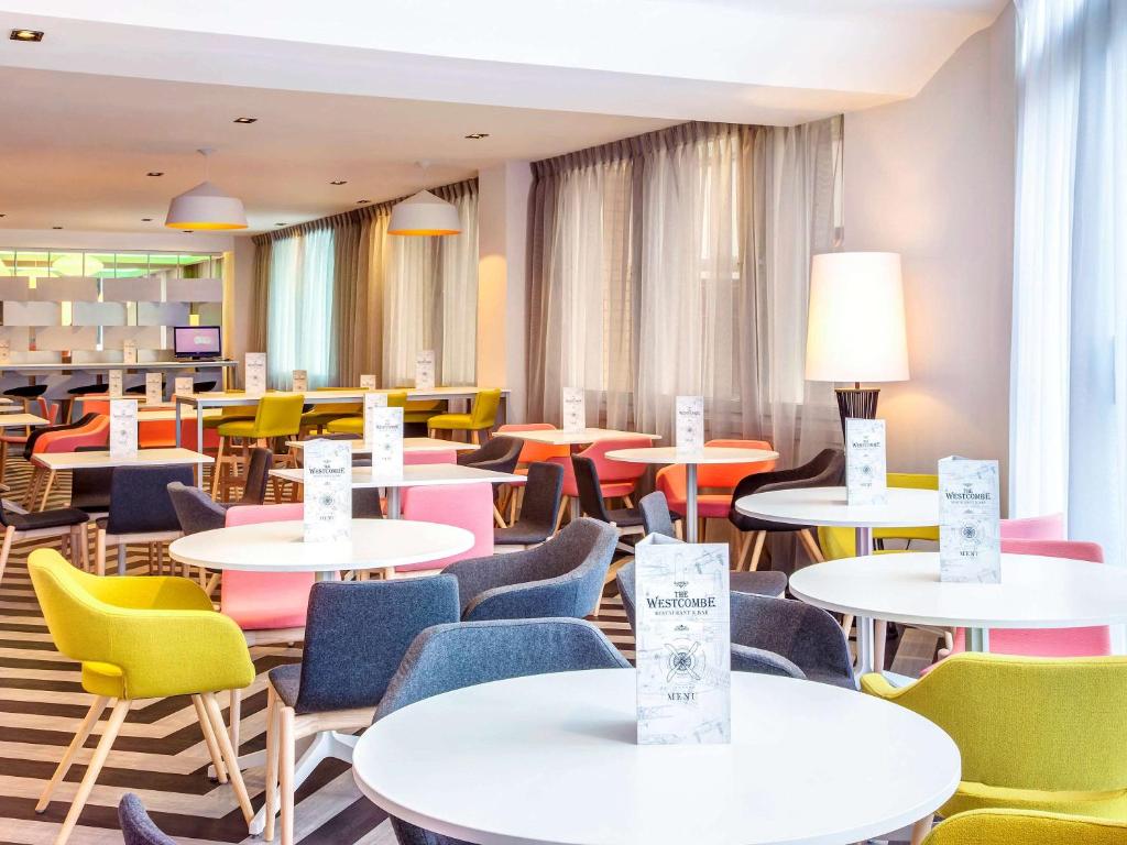 uma cafetaria com mesas e cadeiras e mesas coloridas em ibis Styles London Heathrow Airport em Hillingdon