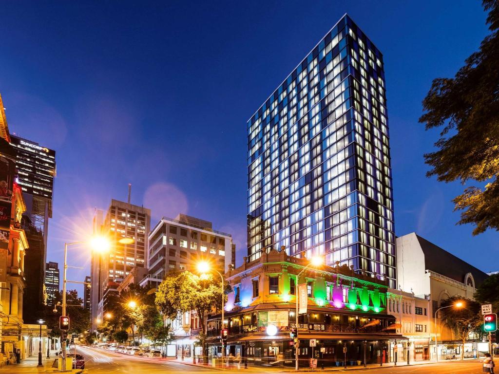 a tall building on a city street at night at ibis Styles Brisbane Elizabeth Street in Brisbane