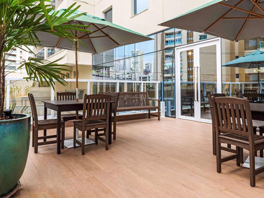 une terrasse avec une table, des chaises et des parasols dans l'établissement ibis Styles Ribeirao Preto Jardim Botanico, à Ribeirão Preto